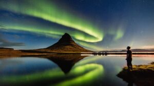 Aurore boréale dans le ciel norvégien illuminant un paysage enneigé avec des montagnes en arrière-plan